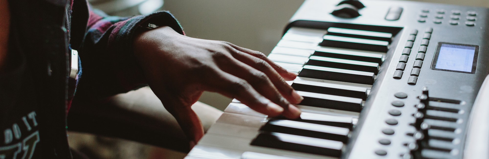 A photo of a left hand playing an F sharp with middle finger on an electric piano keyboard